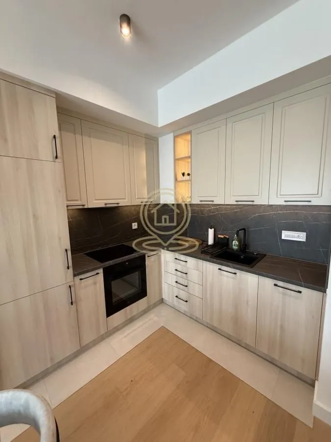 Modern kitchen in light tones with built-in appliances and a dark countertop.