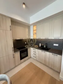 Modern kitchen in light tones with built-in appliances and a dark countertop. - image 2