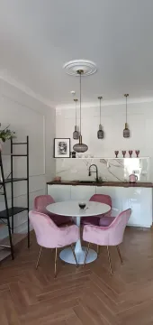Trpezarija sa modernim stolom i roze stolicama uz ugradnu kuhinju. - image 3