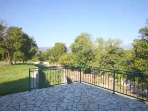 Tiled terrace with a metal railing and a view of greenery and the yard. - image 9