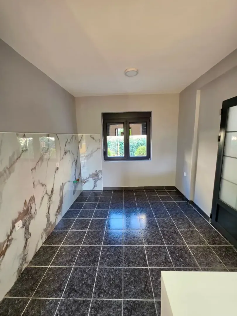 Empty kitchen with ceramic tiles and a window.