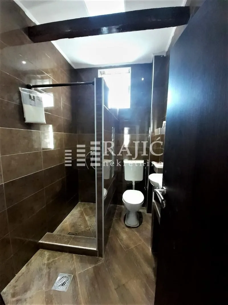 Small bathroom with a walk-in shower and dark tiles.