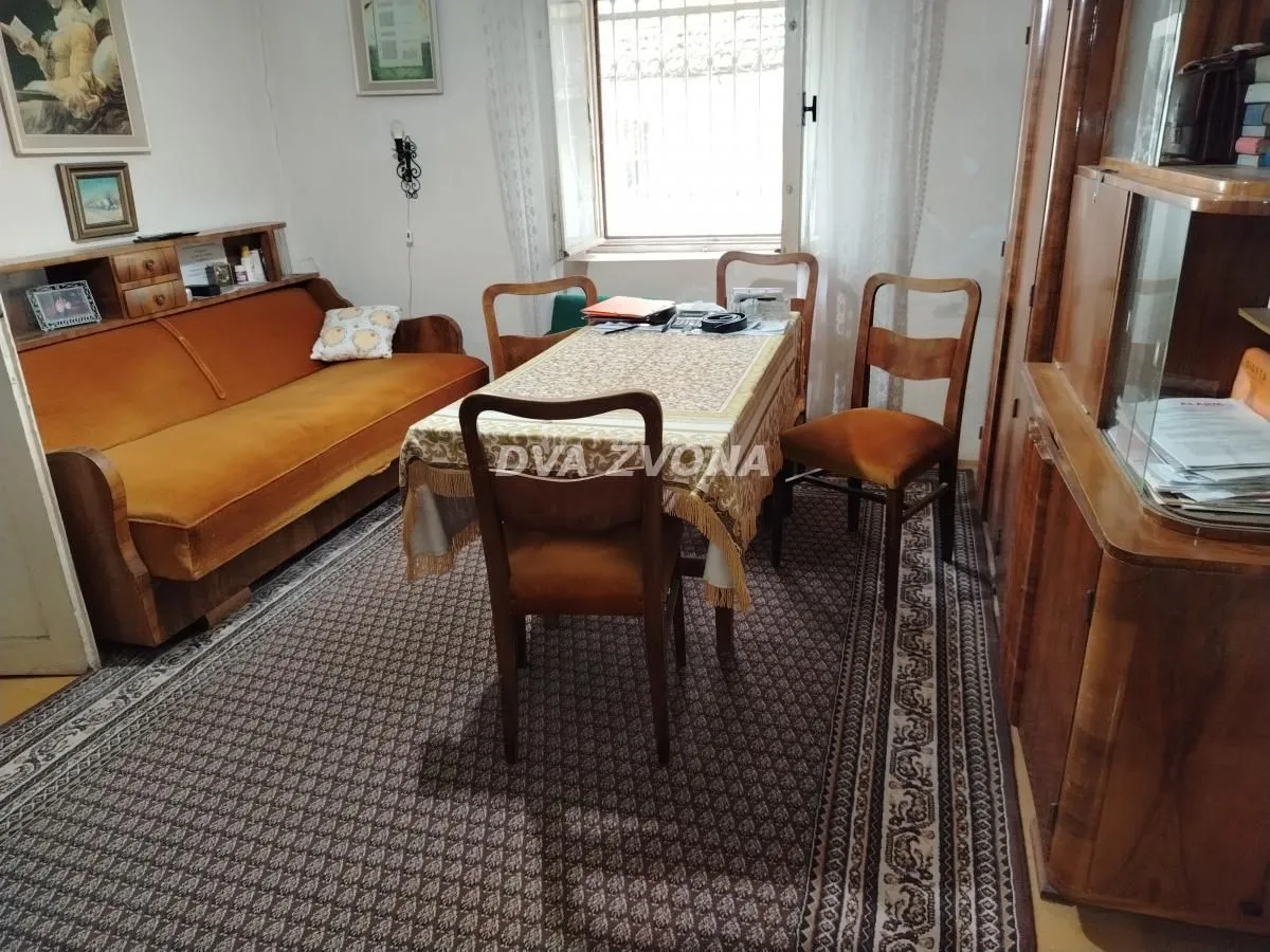 Dnevna soba sa garniturom za sedenje, trpezarijskim stolom i drvenim nameštajem.