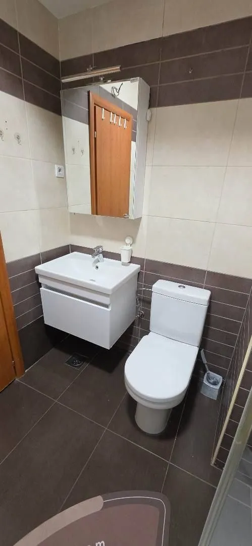 Kupatilo opremljeno umivaonikom, WC šoljom i ogledalom sa ormarićem.