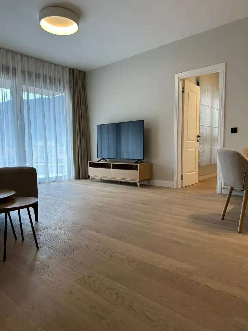 Living room with wooden flooring, TV unit, and access to the terrace.