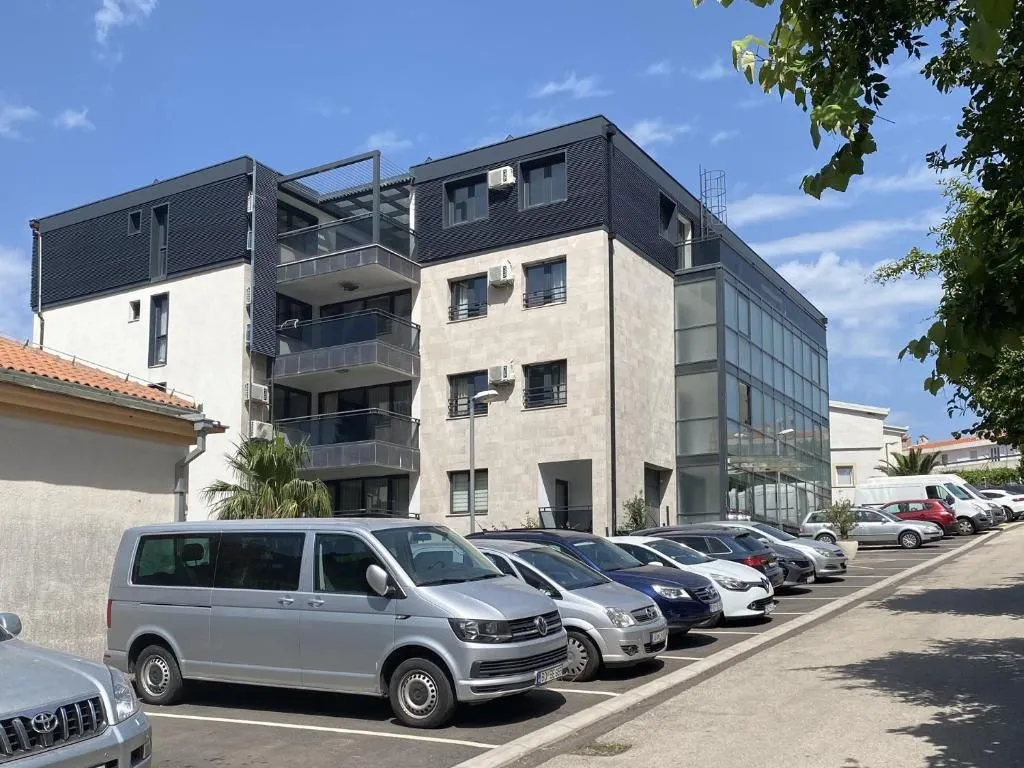 View of the exterior of the building with a parking lot and parked vehicles.