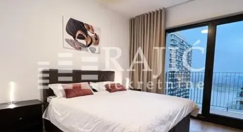 Furnished bedroom with a double bed and large balcony doors. - image 6