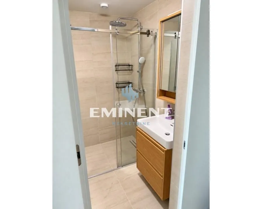 Modernly equipped bathroom with a walk-in shower and a vanity unit.