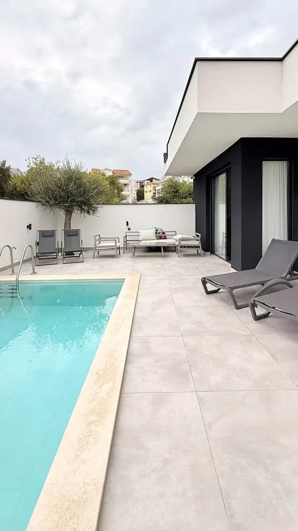Yard with a swimming pool and outdoor seating furniture in front of the house.