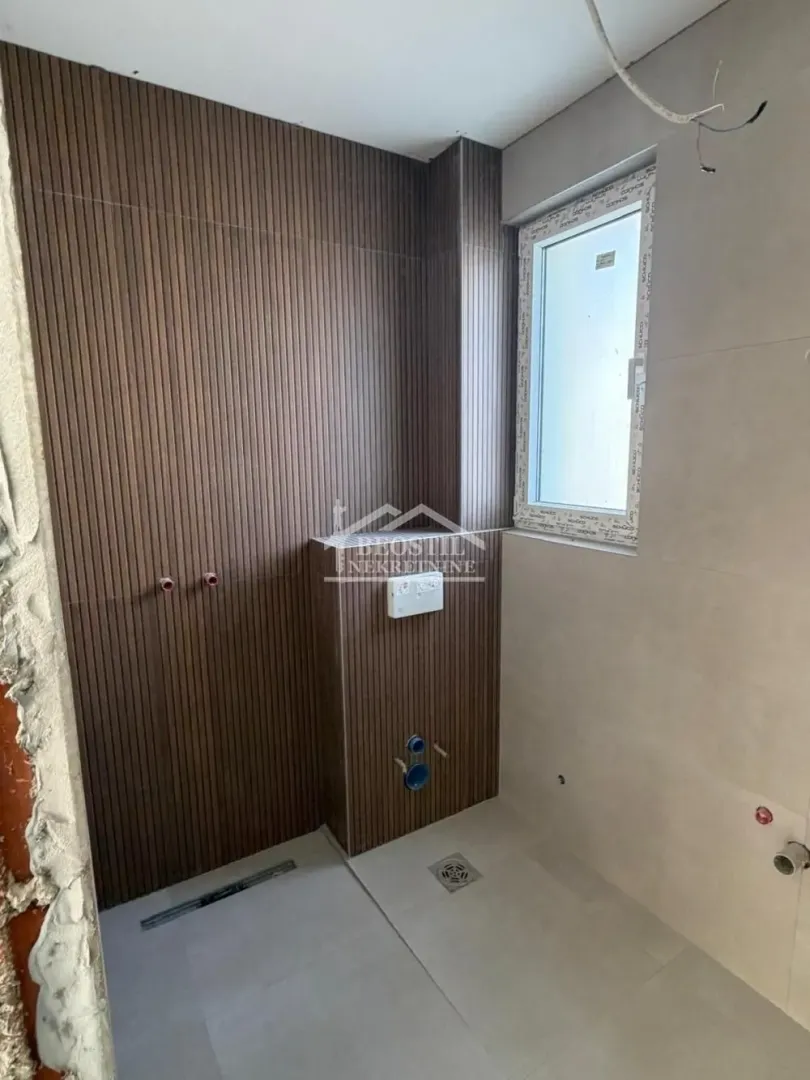 Kupatilo u fazi renoviranja sa zidnim oblogama i postavljenim keramičkim pločicama.