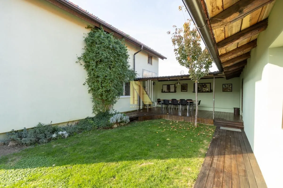 House yard with a maintained lawn area and a covered wooden terrace.