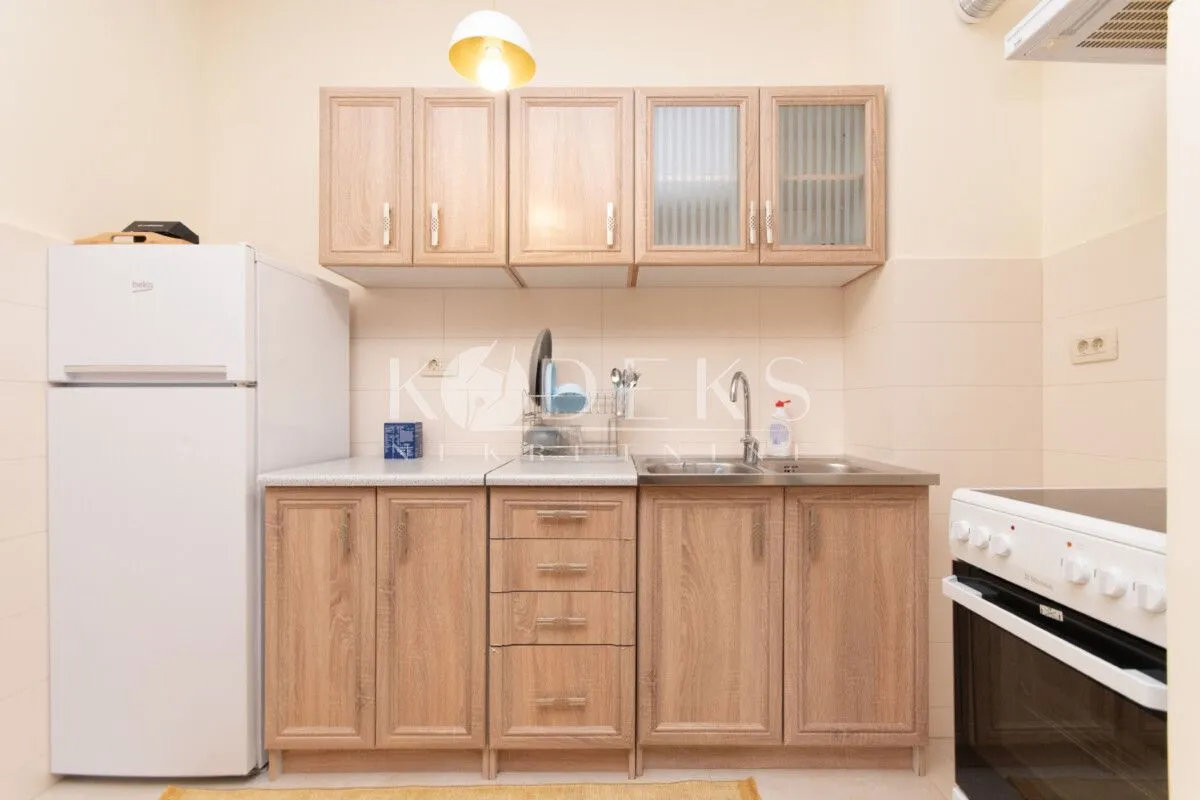 Compact kitchen with wooden cabinets, refrigerator, and stove.
