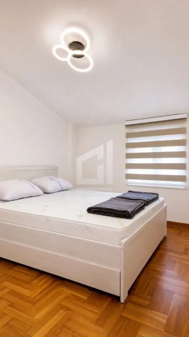 Bedroom with a double bed, hardwood flooring, and a window with blinds.