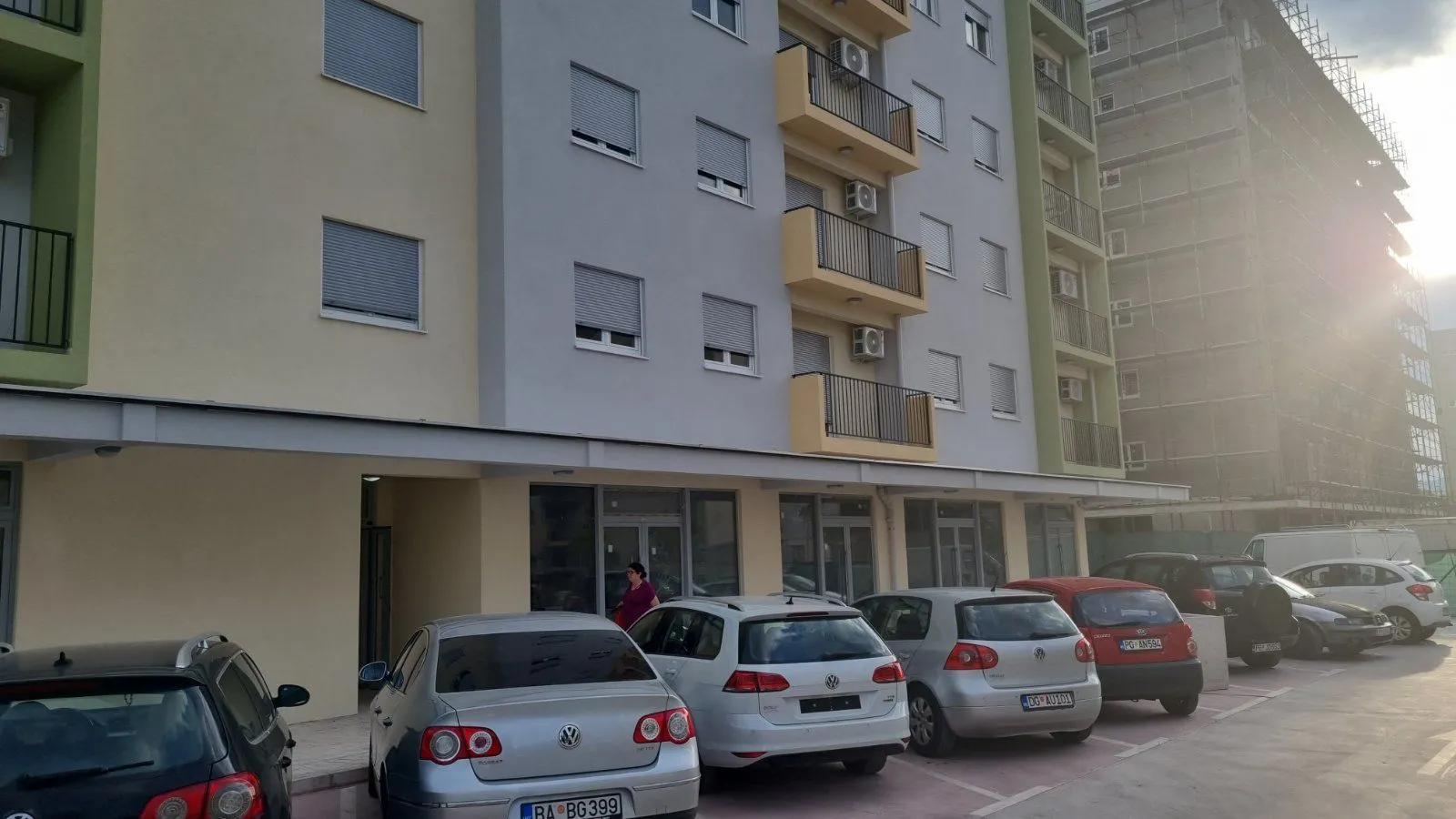 Exterior view of an apartment building with parking in front of the entrance.