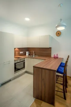 Moderna kuhinja sa drvenim elementima i šankom za ručavanje. - image 3