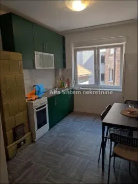 Kuhinja sa zelenim elementima, trpezarijskim stolom i starom peći na drva. - image 5