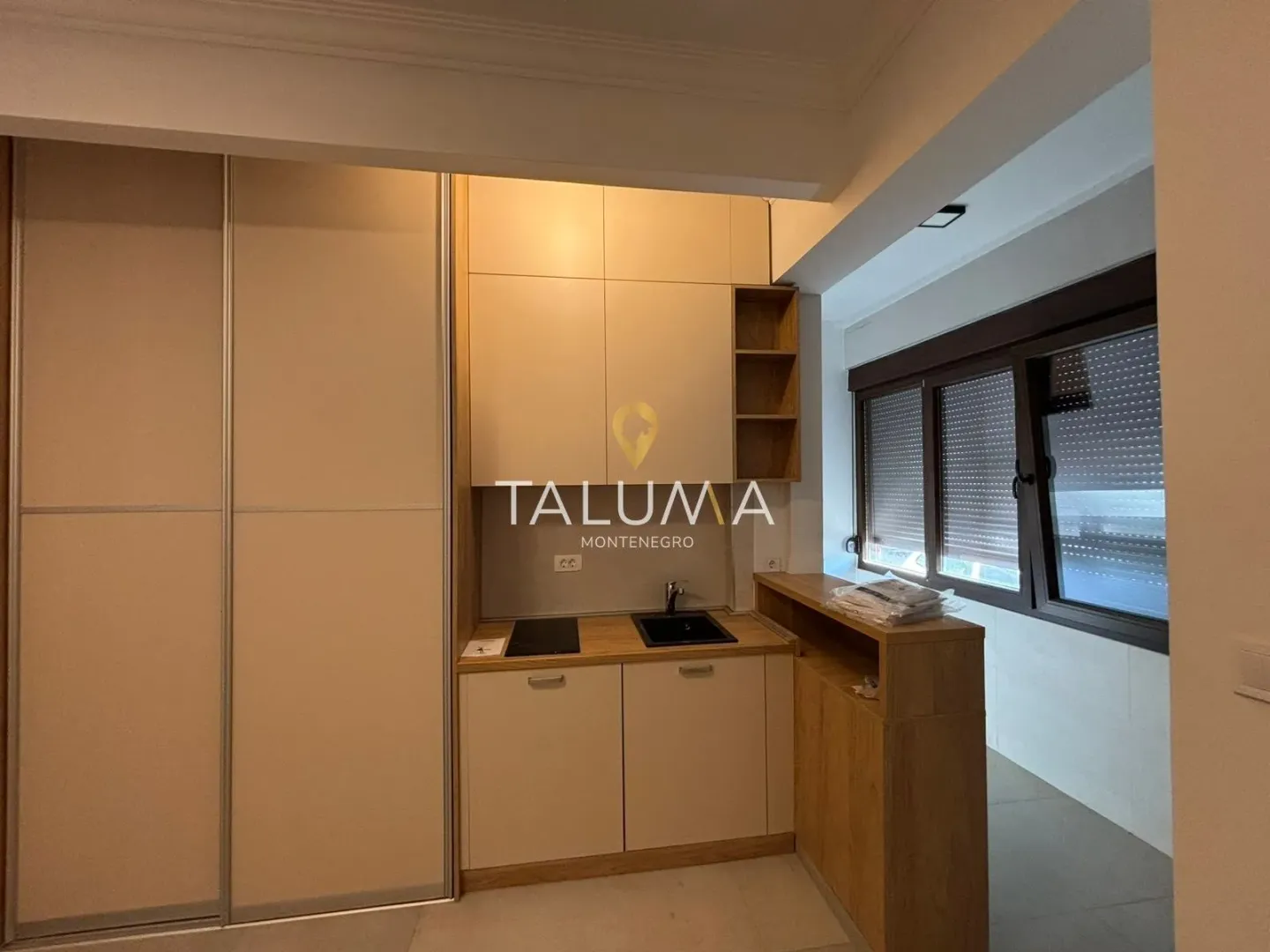 Small kitchen with light-colored cabinetry and a built-in wardrobe.