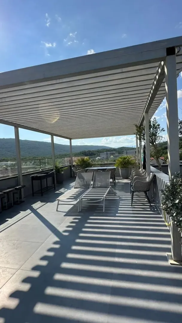 Prostrana krovna terasa sa garniturom za sjedenje i ležaljkama.