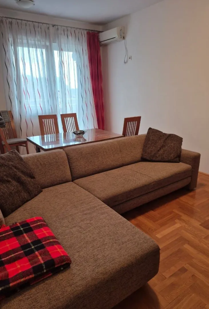 Dnevna soba sa ugaonom garniturom i trpezarijskim stolom.