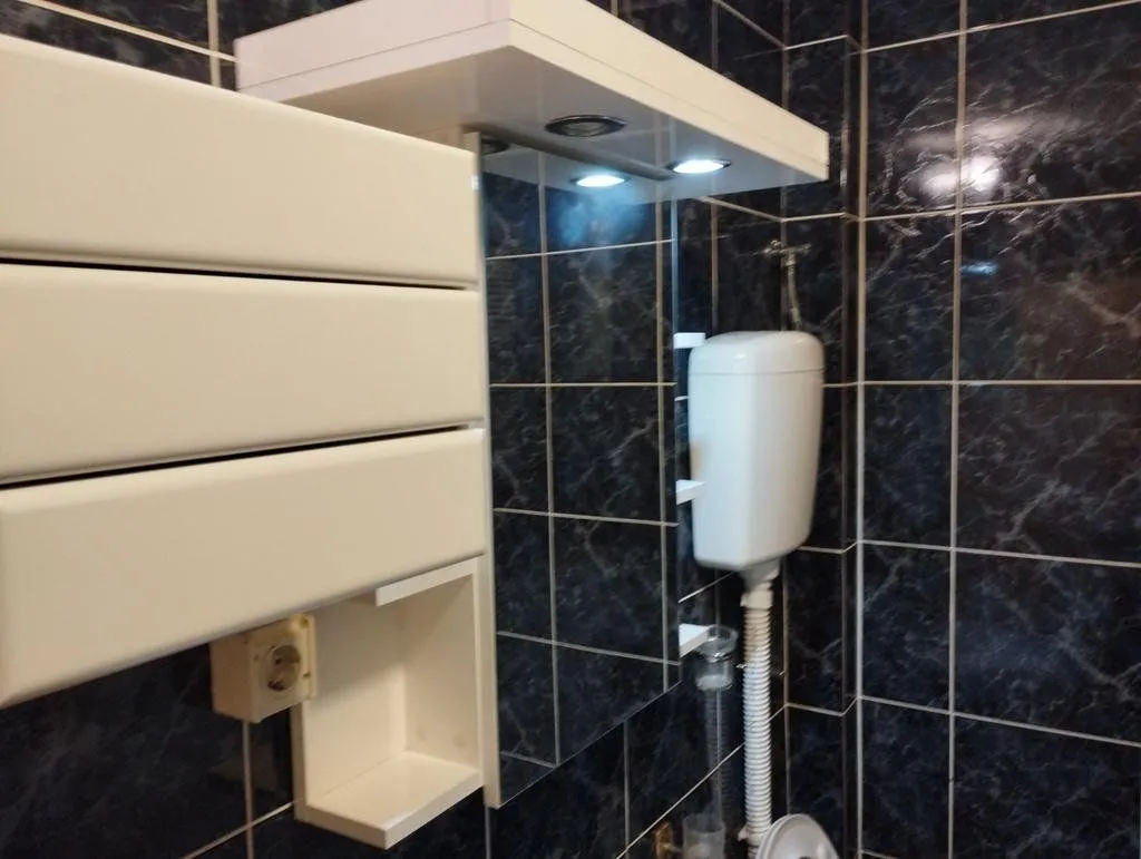 Bathroom with dark tiles and white fixtures.
