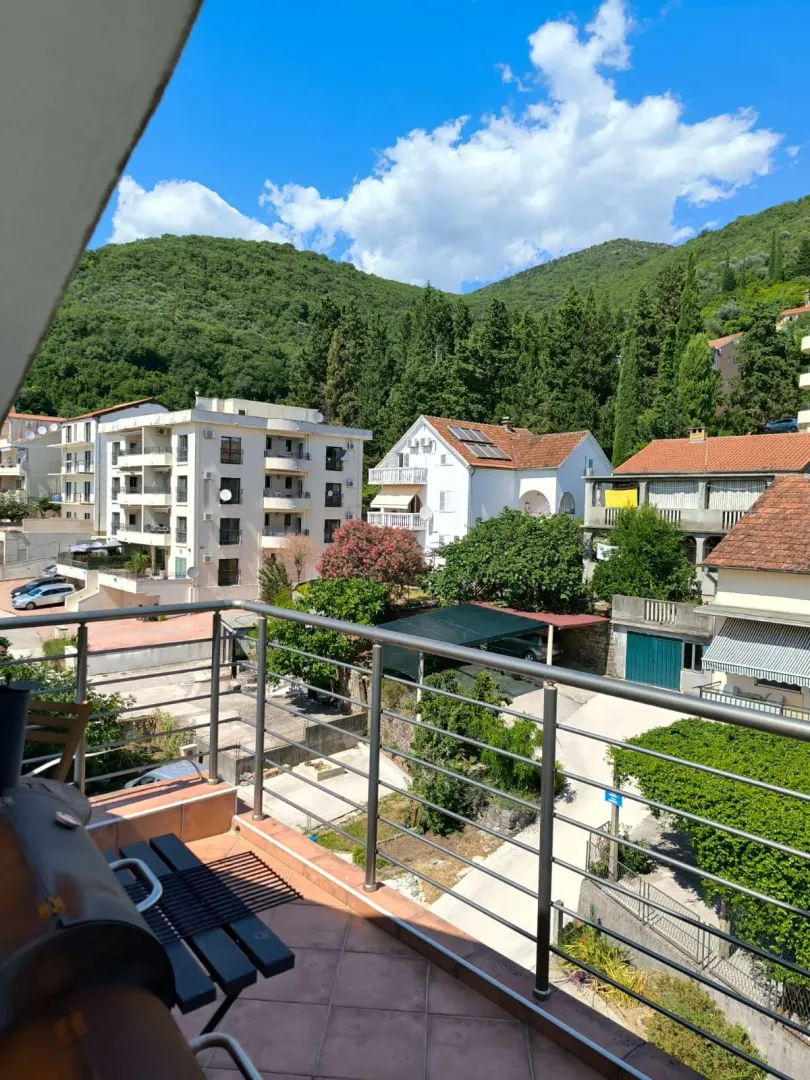 Pogled sa terase na okolne zgrade, zelenilo i brda.