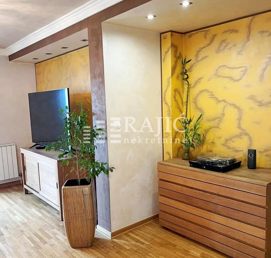 Living room with a wooden chest of drawers, television, and decorative wall panels.