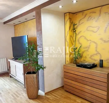 Living room with a wooden chest of drawers, television, and decorative wall panels. - image 2