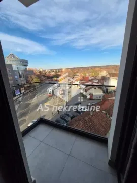 Small tiled balcony with a glass railing and a view of the street and surrounding buildings. - image 21