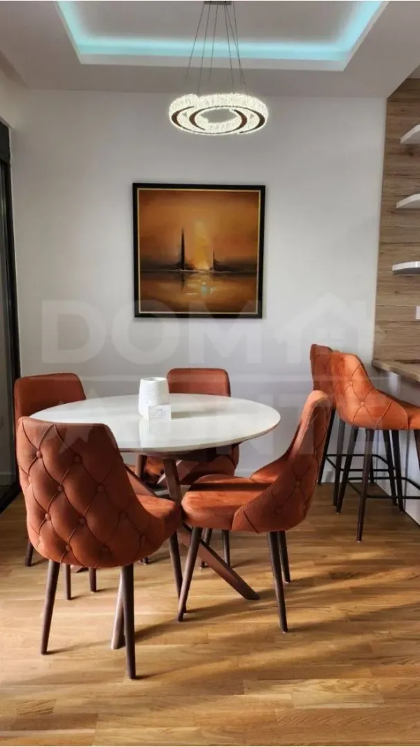 Modern dining room with a round table and orange chairs.