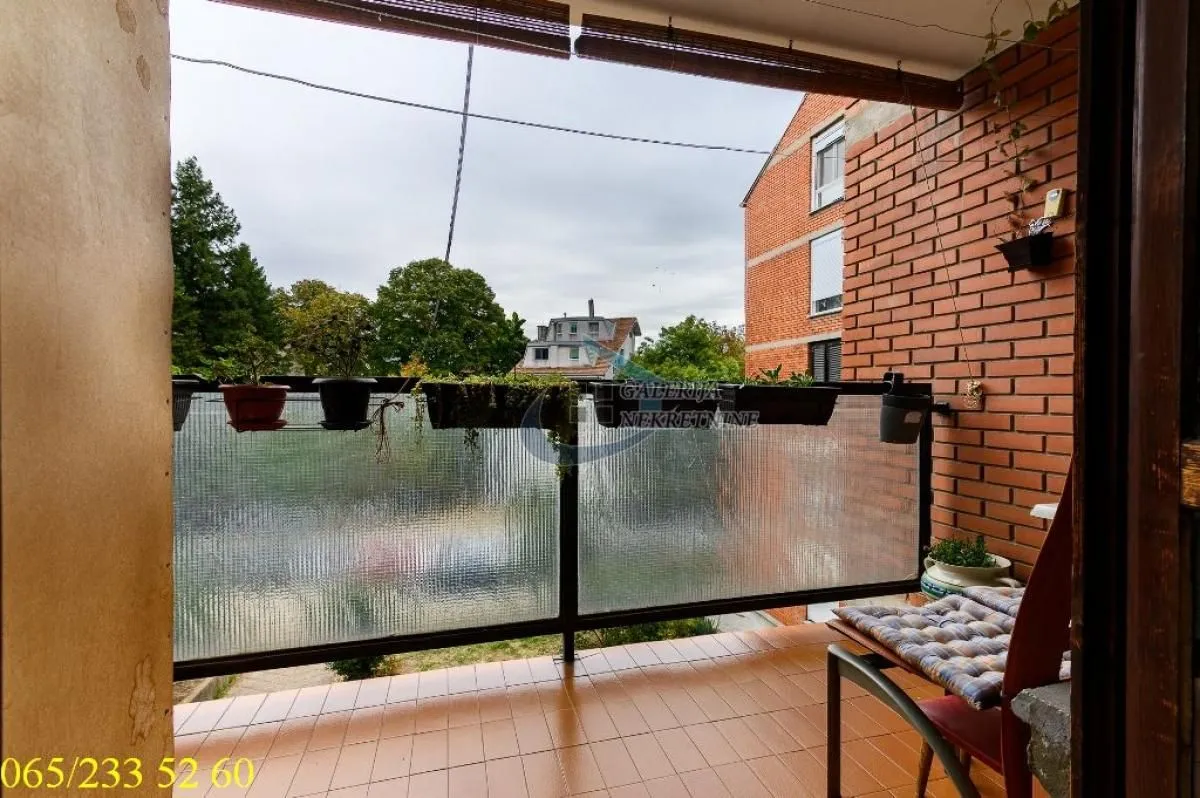 Covered balcony with a view of the surrounding greenery and buildings.