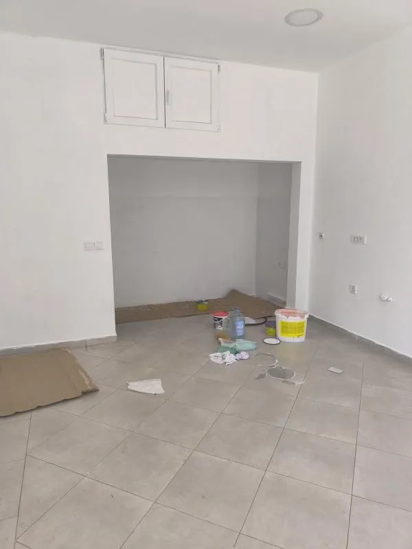 Empty room with ceramic floor tiles and painting supplies.