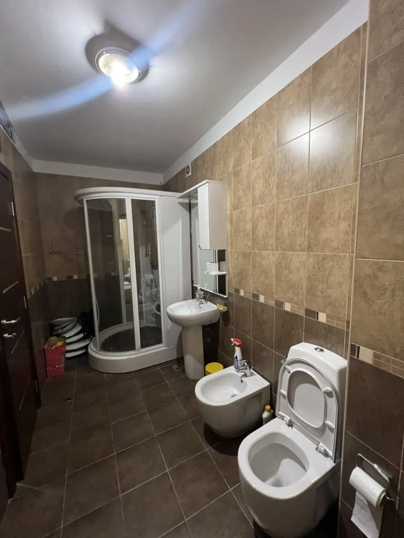 A bathroom with a shower cabin, bidet, and toilet.