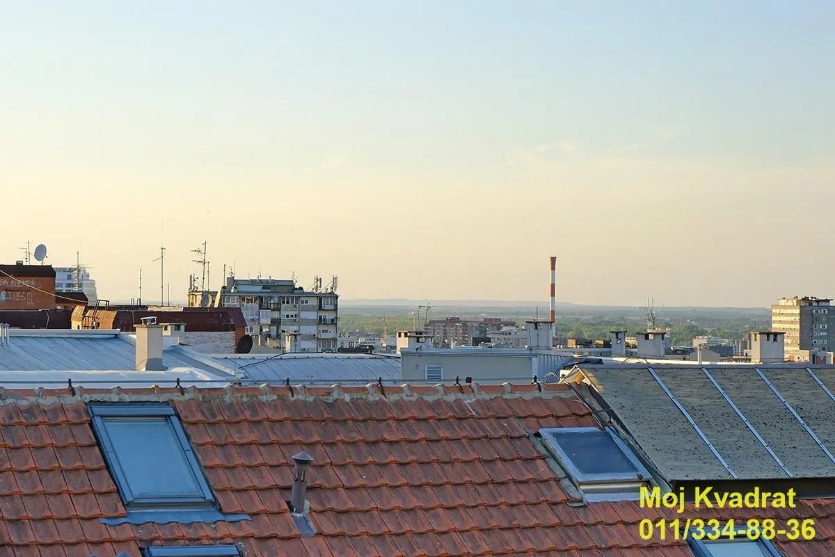Pogled sa prozora ili terase na krovove zgrada i okolno naselje.