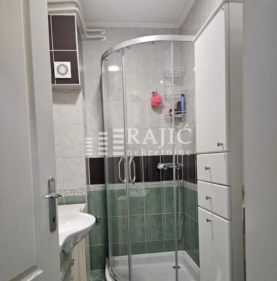 Smaller bathroom with a shower cabin and a white cabinet.