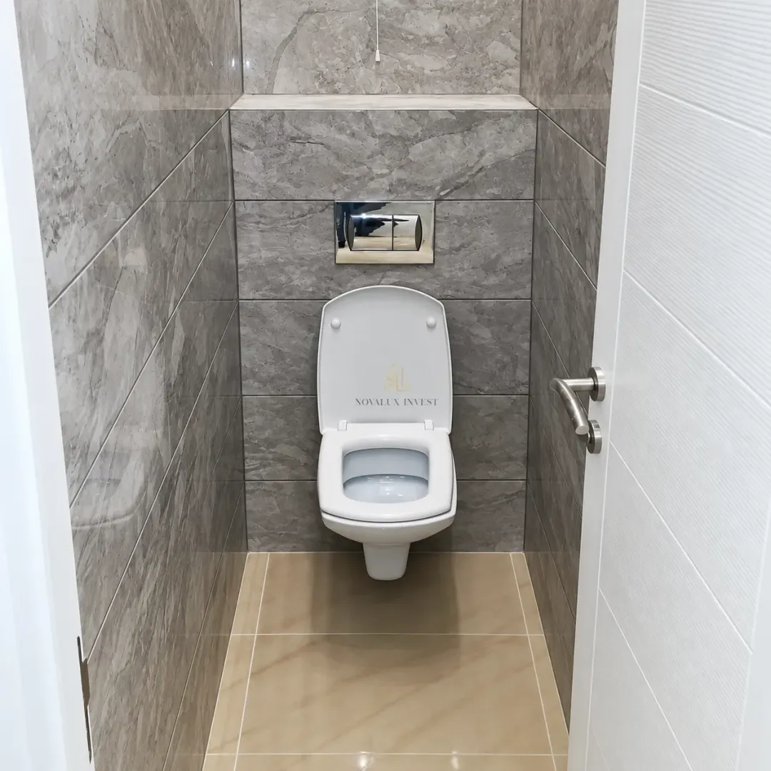 Small bathroom lined with grey tiles and a wall-hung toilet.