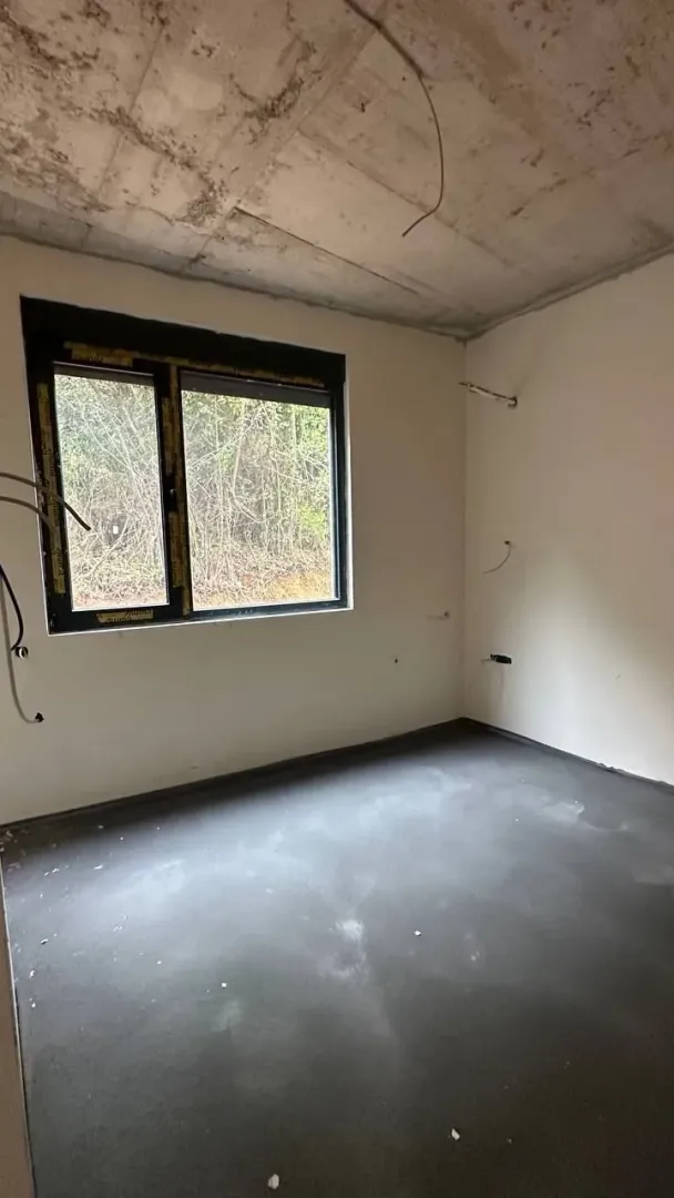 Nepreuređena prostorija u sivoj fazi izgradnje sa prozorom.