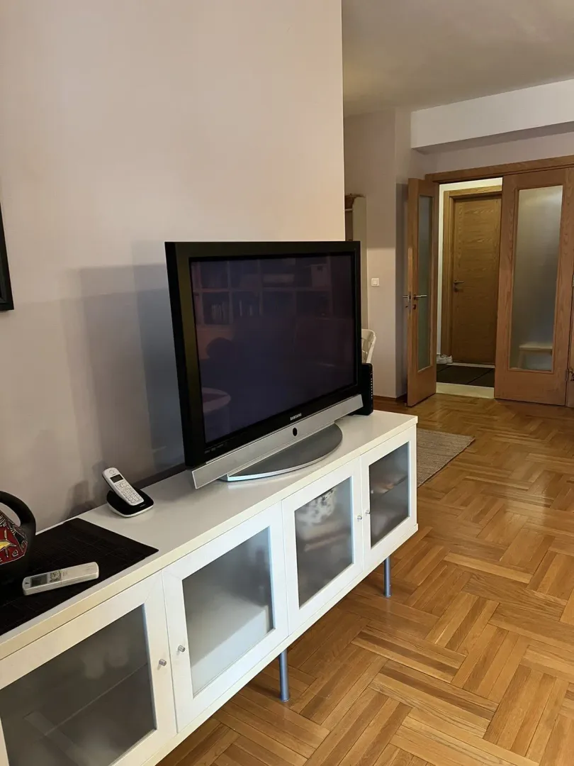 Dio dnevne sobe sa televizorom na komodi i parketom.