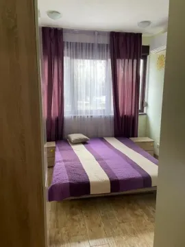 Bedroom with a double bed, a window with purple curtains, and bedside tables. - image 9