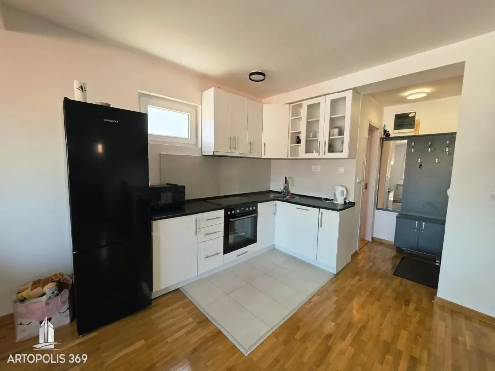 Small kitchen with white cabinets and a black refrigerator.