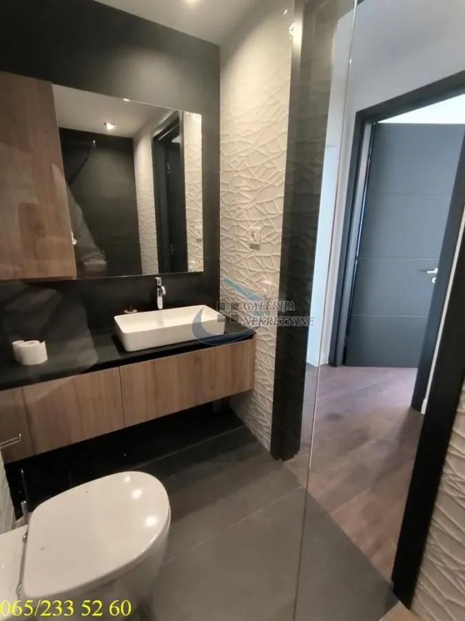 Moderno kupatilo sa umivaonikom, ogledalom i WC šoljom.