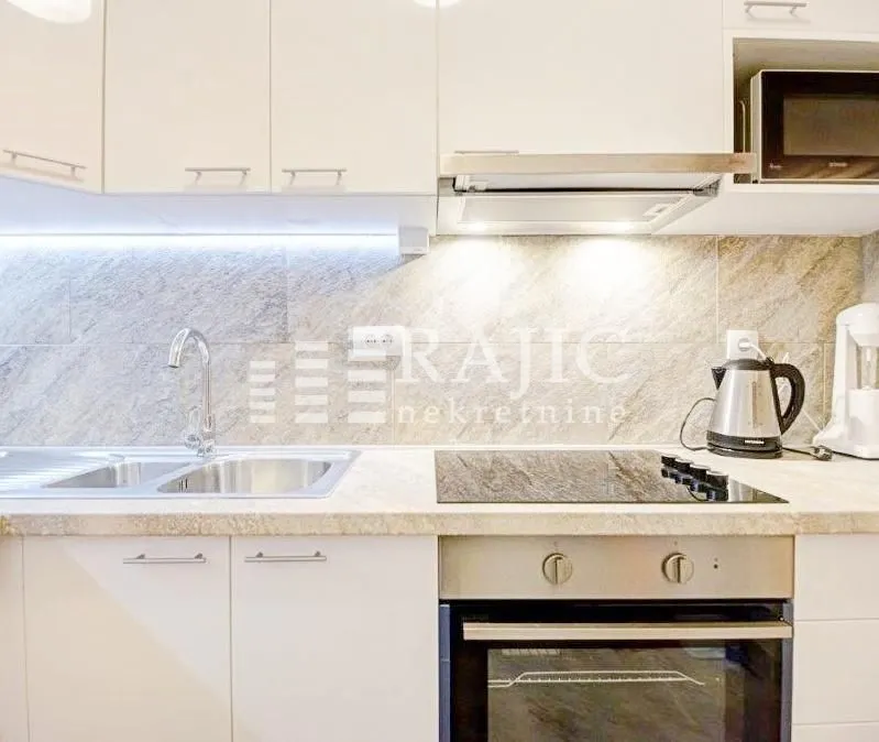 Modern kitchen with white cabinets, built-in oven and cooktop.