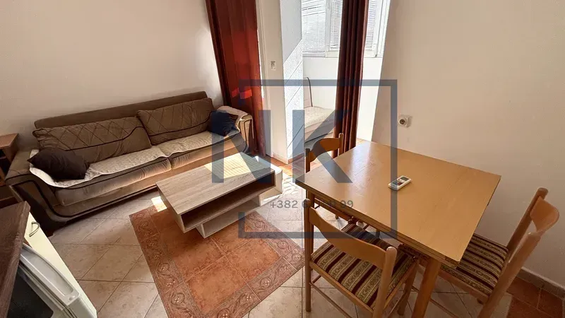 Living room with a sofa, coffee table, and dining table with chairs.