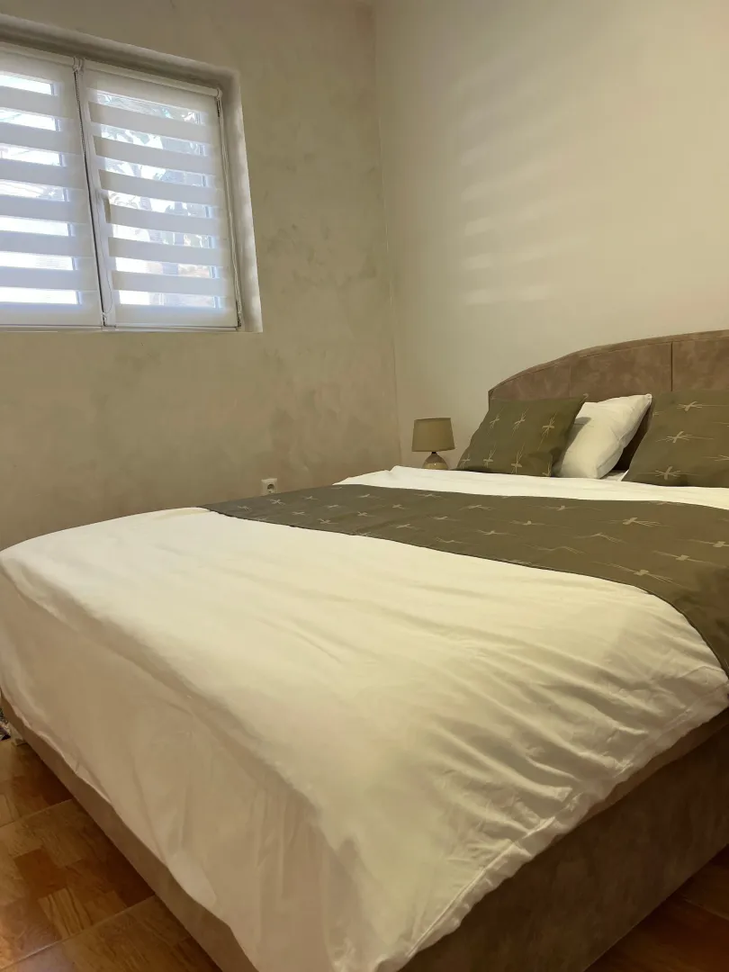 Furnished bedroom with a double bed and a window.