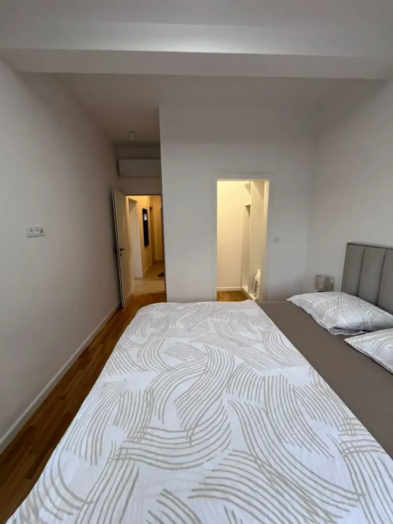 Pogled na spavaću sobu sa bračnim krevetom i prolazom ka hodniku.