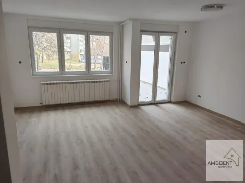 Empty room with laminate flooring, white walls, a window, and doors leading to a terrace. - image 3