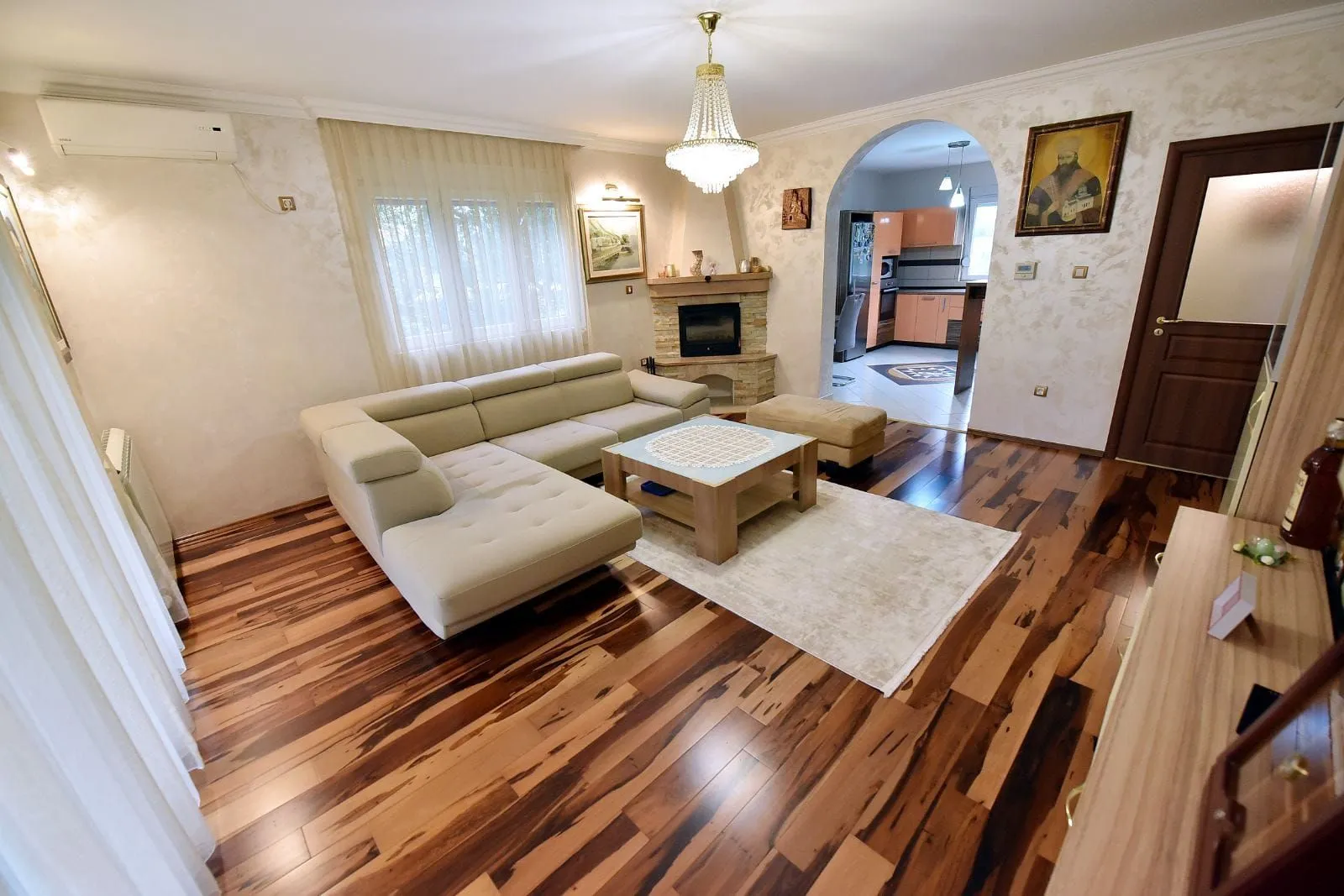Spacious living room with a sofa set, fireplace, and a view of the kitchen.