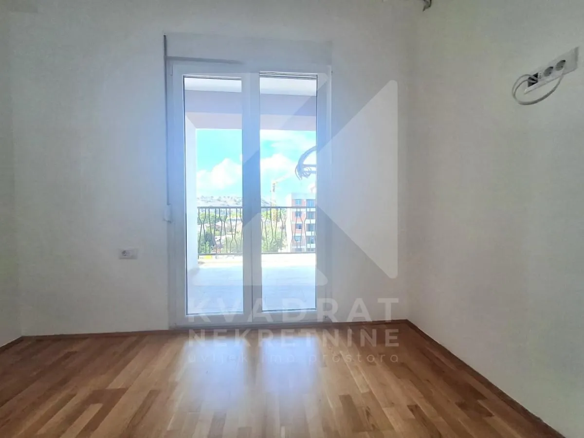 Empty room with hardwood floors and balcony doors leading to the terrace.