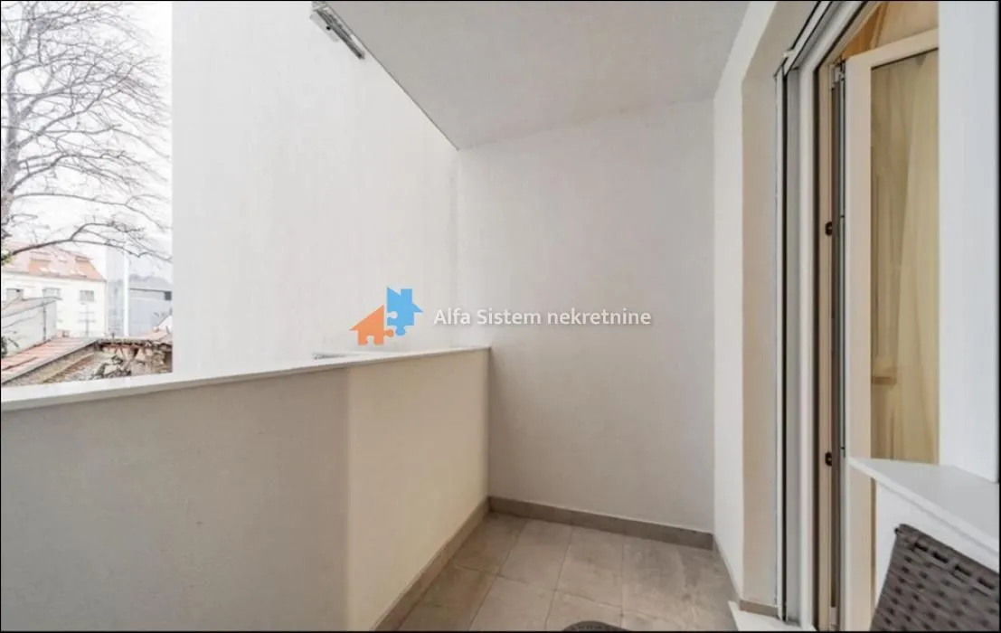 Smaller covered balcony area with ceramic tiles and a view of surrounding buildings.
