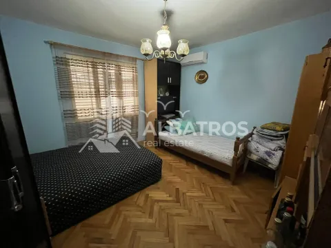 Spavaća soba sa dva kreveta, parketom na podu i prozorom sa roletnama. - image 6