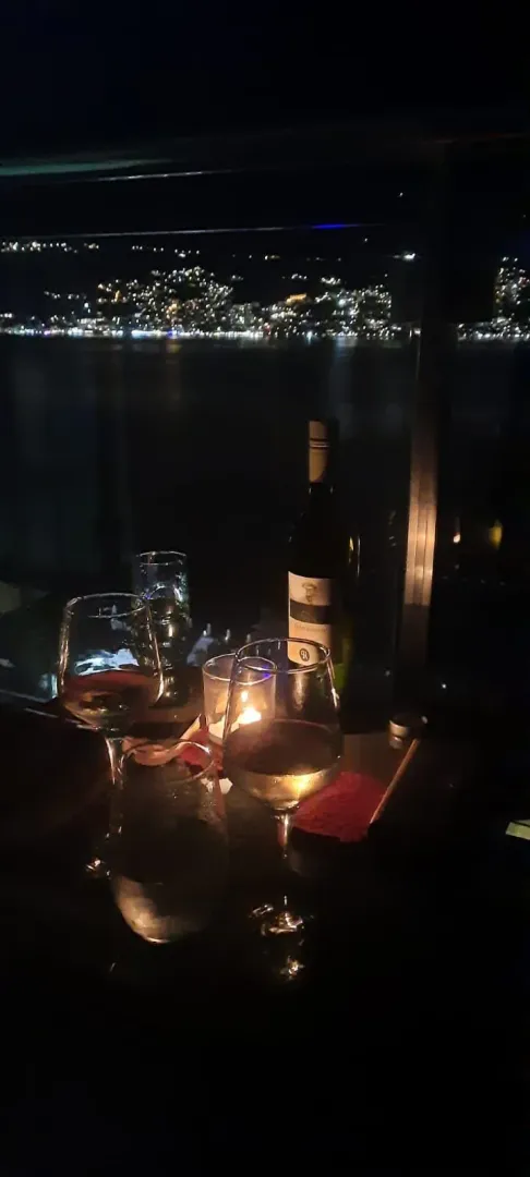 Noćni pogled sa terase na osvijetljeni grad i more.